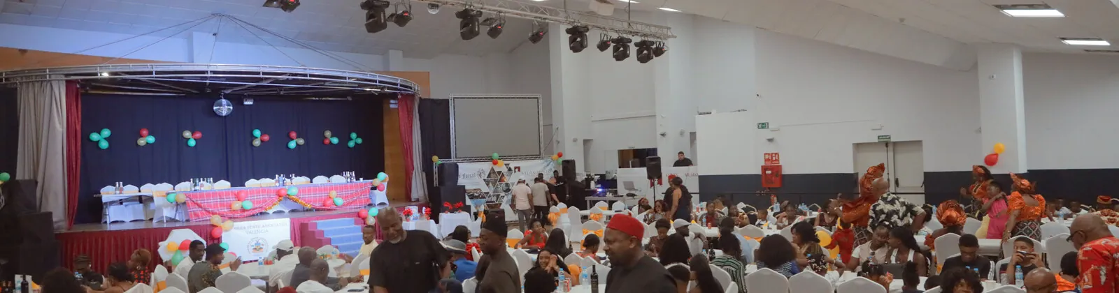 El salón del 20.º aniversario con las mesas llenas y el escenario al fondo