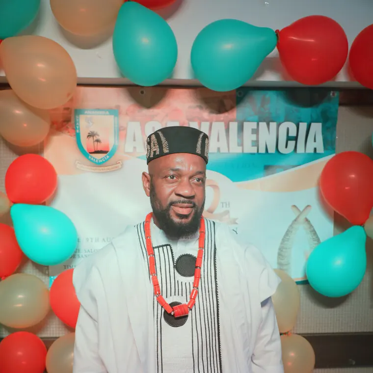 Invitado con atuendo blanco, gorra roja y collar de coral